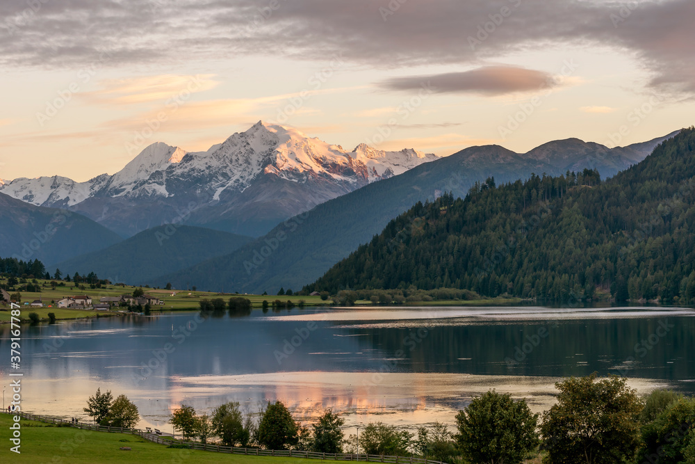 Colorful sunset on Lago della Muta lake, with the snowy Mount Ortles in the background, South Tyrol, Italy, reflected in the water