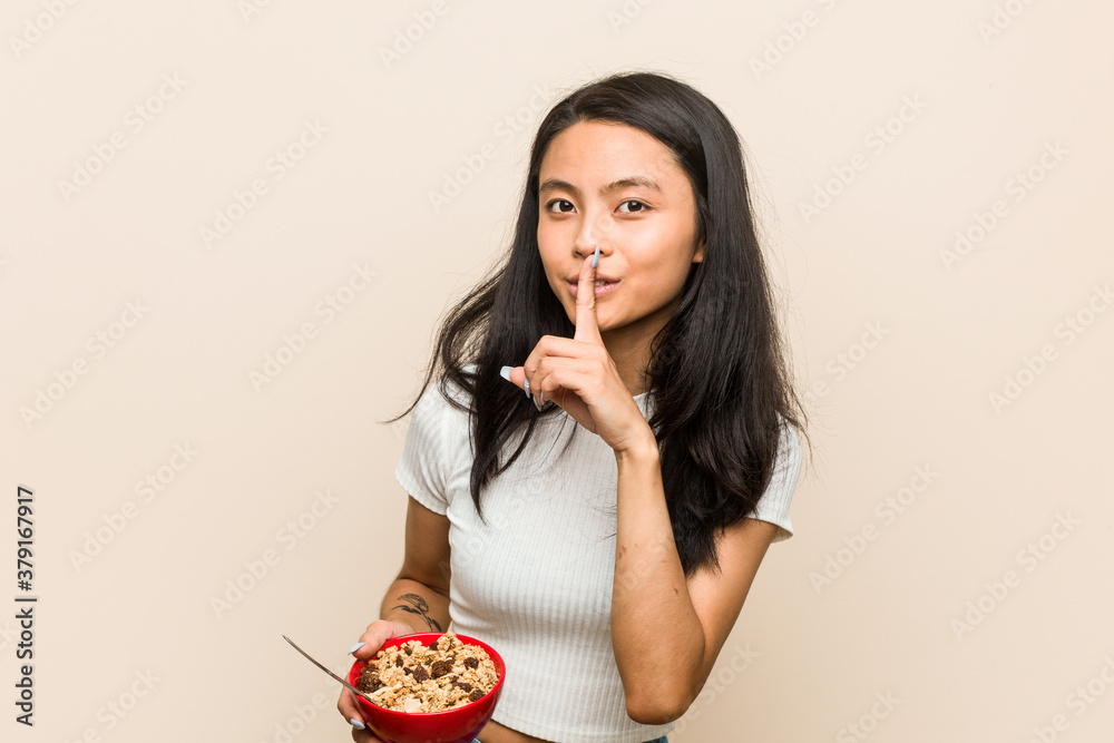 Young asian woman holding a cereals bowl keeping a secret or asking for silence. Young asian woman holding a cereals bowl keeping a secret or asking for silence.