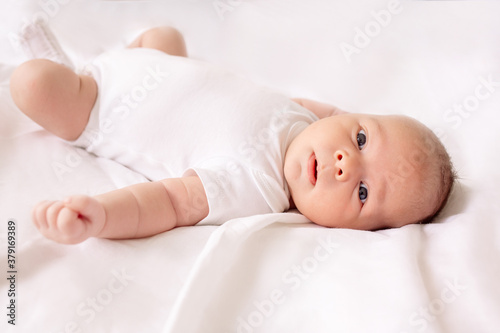 Newborn baby lies  on the bed in the bedroom at home