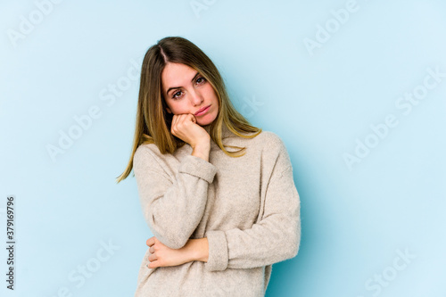 Young caucasian woman isolated on blue background tired of a repetitive task.