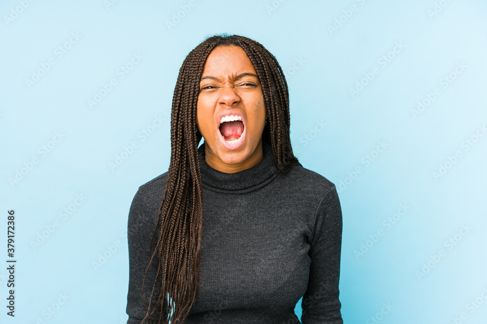 Young african american woman isolated on blue background screaming very angry and aggressive. Young african american woman isolated on blue background screaming very angry and aggressive.