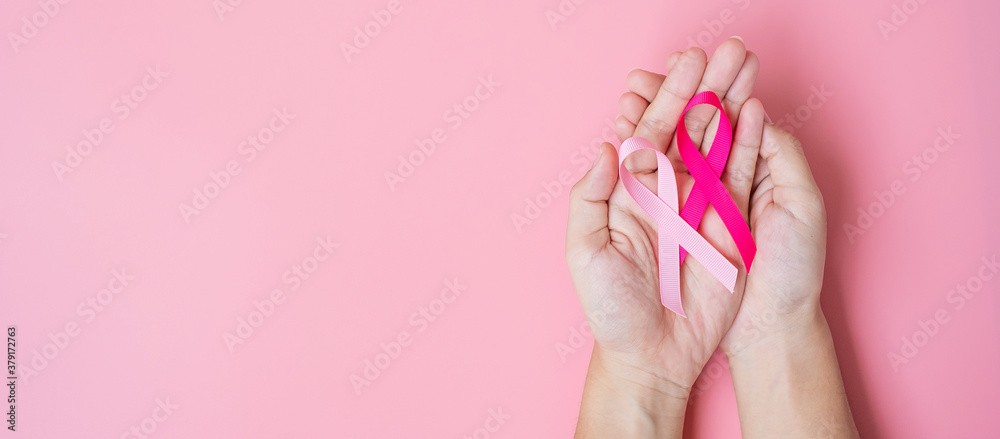 October Breast Cancer Awareness month, adult Woman hand holding Pink Ribbon on pink background for supporting people living and illness. International Women, Mother and World cancer day concept - obrazy, fototapety, plakaty 