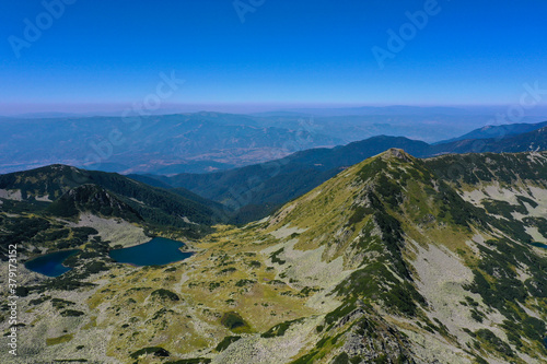 Amazing alpine lake at the mountains, high alpine green peak, sunny summer day, drone flight.