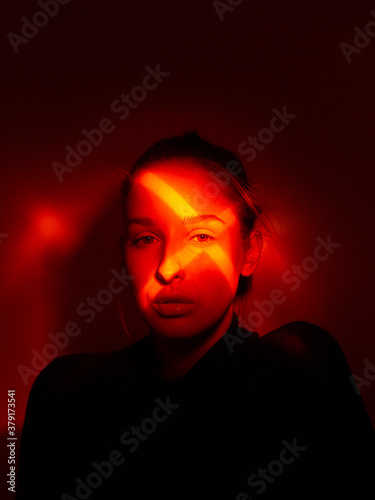 Creative portrait of young girl with cross shaped red light on her eye. Halloween party poster
