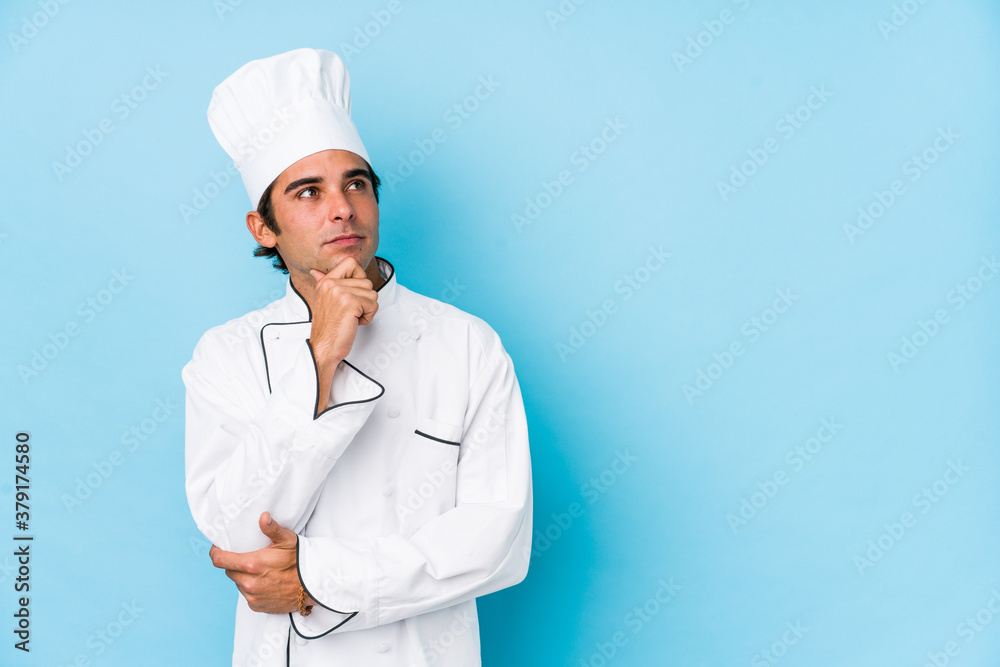 Young cook man isolated looking sideways with doubtful and skeptical expression.