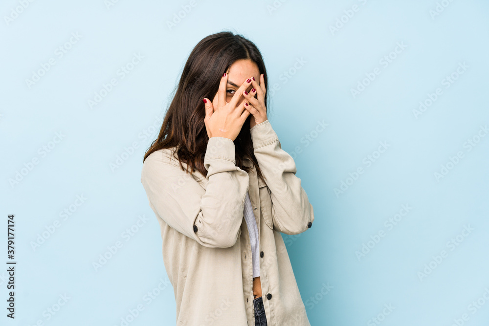 Young mixed race hispanic woman isolated blink at the camera through fingers, embarrassed covering face. Young mixed race hispanic woman isolated blink at the camera through fingers, embarrassed covering face.