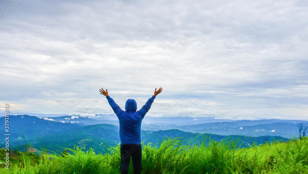 A happy traveler, standing on the grass, admiring the beautiful mountain scenery. People enjoy nature Back view A happy traveler, standing on the grass, admiring the beautiful mountain scenery. People enjoy nature Back view