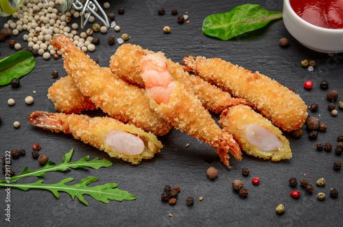 Fried Shrimps tempura with sweet chili sauce on a black stone board