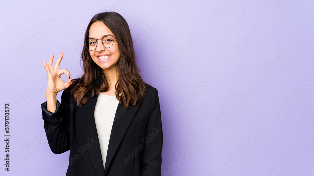 Young mixed race hispanic woman isolated winks an eye and holds an okay gesture with hand. Young mixed race hispanic woman isolated winks an eye and holds an okay gesture with hand.