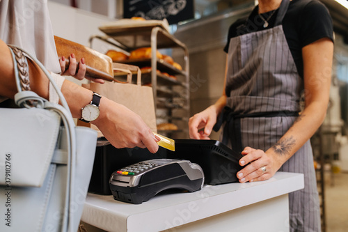 Paying with her credit card in a bakery shop, making a purchaise