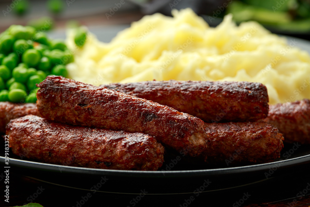 Vegetarian vegan sausages with mashed potato and green peas in black plate Vegetarian vegan sausages with mashed potato and green peas in black plate