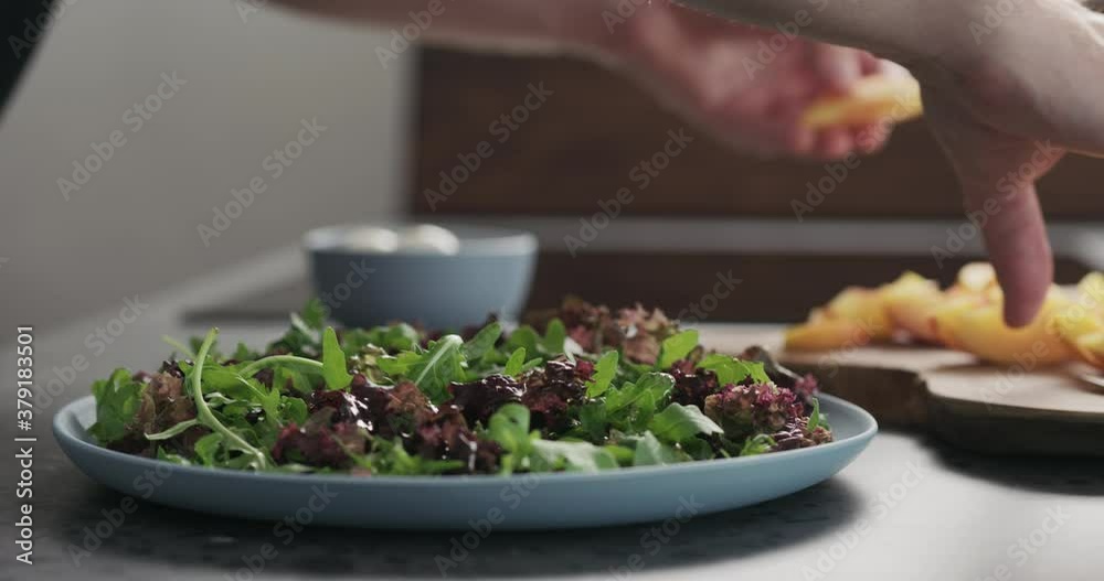 Slow motion man making salad with nectarines and mozzarella on a blue plate on concrete countertop on kitchen, add nectarines