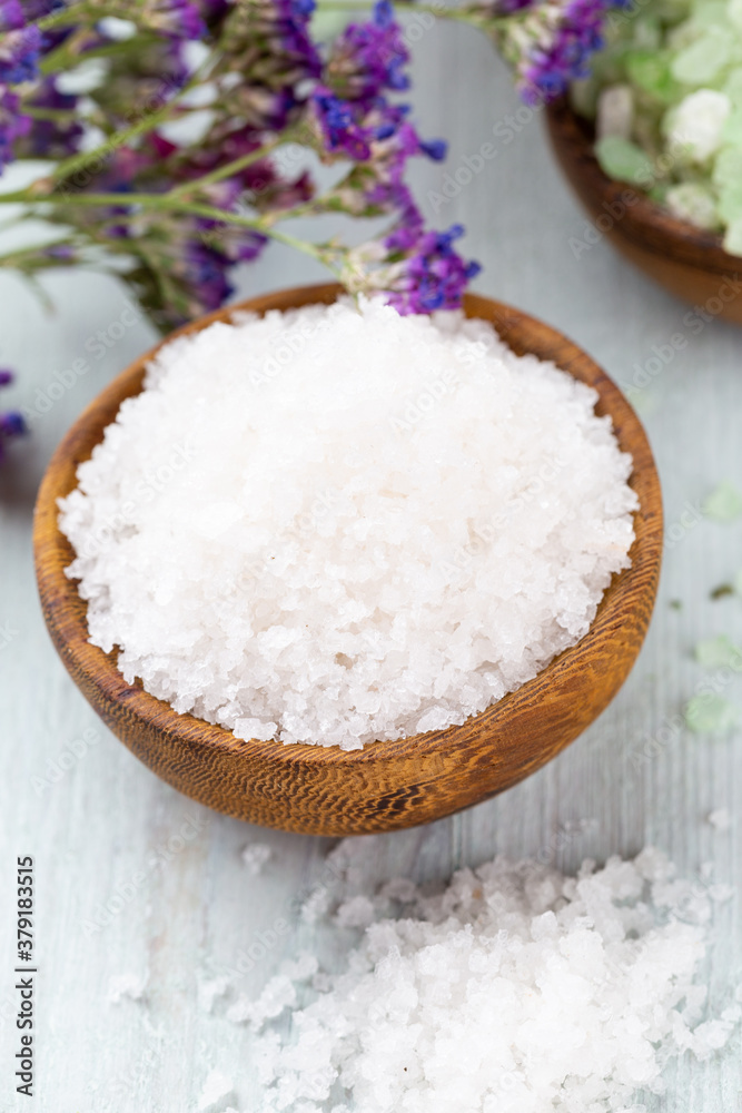 Sea salt in bowl, aroma oil in bottles, Wellness and flowers on grey textured background and flowers on vintage wooden background. Selective focus. Sea salt in bowl, aroma oil in bottles, Wellness and flowers on grey textured background and flowers on vintage wooden background. Selective focus.