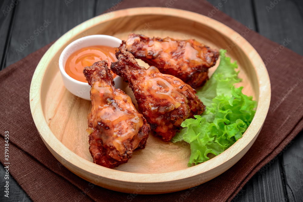 BBQ chicken wings with spicy sauce on a wooden plate BBQ chicken wings with spicy sauce on a wooden plate