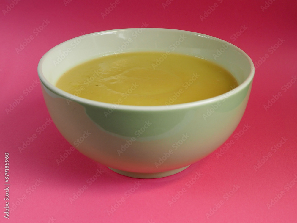 green and white plate with cream soup of zucchini, potatoes, cream, onions on a pink background side view . cooking gluten-free food at home green and white plate with cream soup of zucchini, potatoes, cream, onions on a pink background side view . cooking gluten-free food at home
