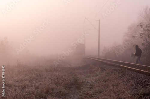 A man crosses the rails. Cross the road in the wrong place. Restricted area. A man walking on the rails in front of the train.