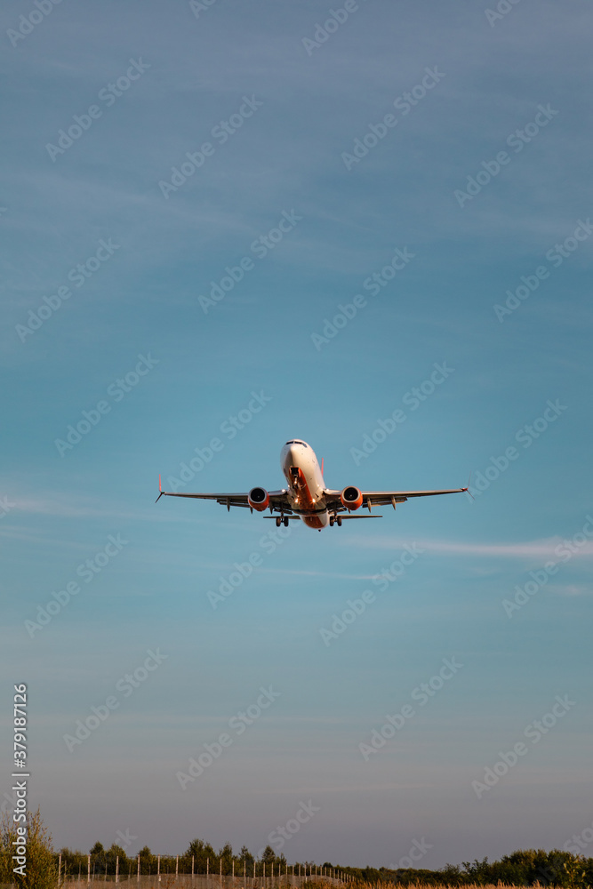 Fototapeta premium view of airplane landing on sunset