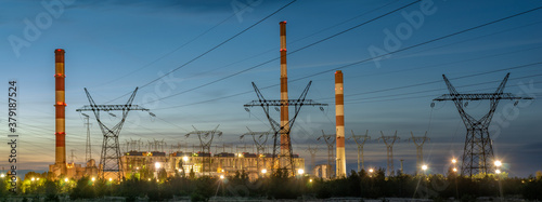 High-voltage pylons running straight from the power plant against the background of the night sky - panorama