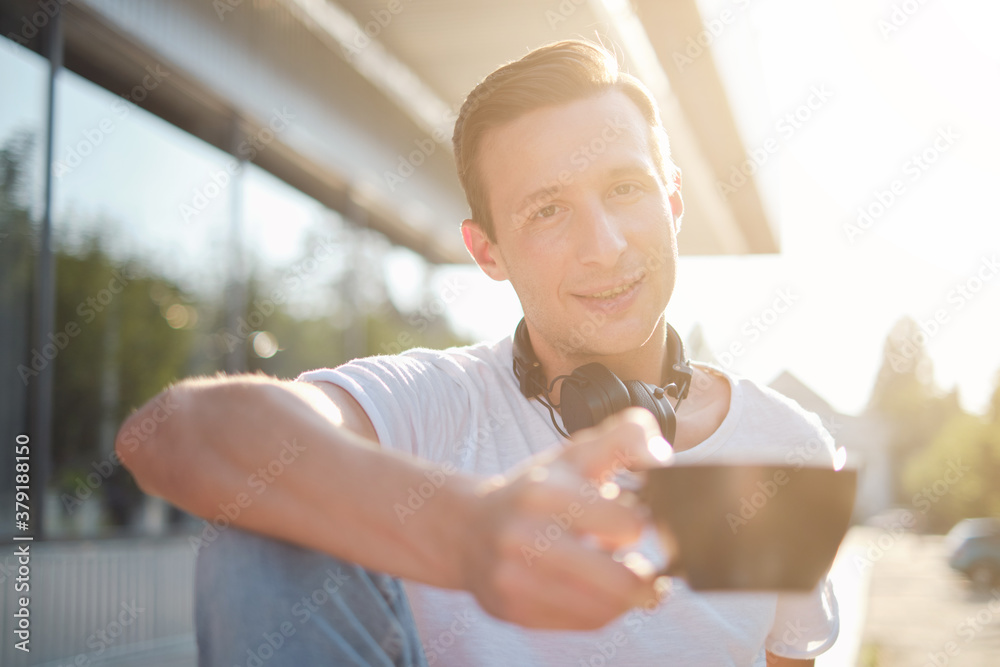 Young attractive man enjoying a cup of aromatic coffee outdoors in sunny weather Young attractive man enjoying a cup of aromatic coffee outdoors in sunny weather