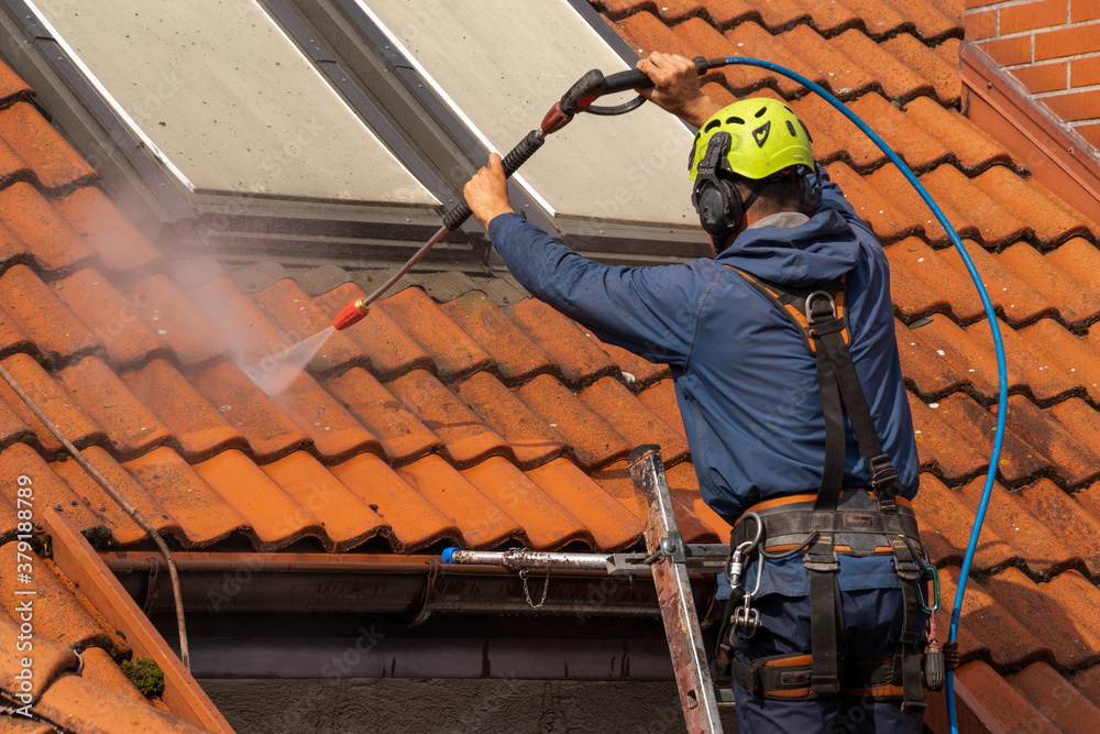 worker washing the roof with pressurized water