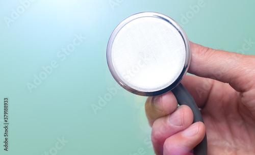 Female hand holds a stethoscope on a blue background. Concept doctor, doctor's appointment, virus, treatment, diagnosis.