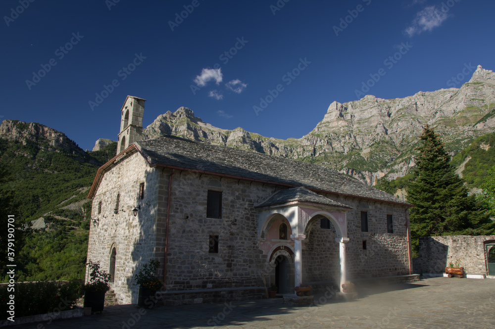 A monastery in the village Katarraktis in national park Tzoumerka in Greece with mountains in the background