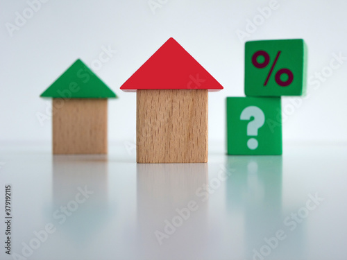 Toy houses made of wooden cubes with question marks and percent marks. Mortgage, insurance, buing and rent concept.