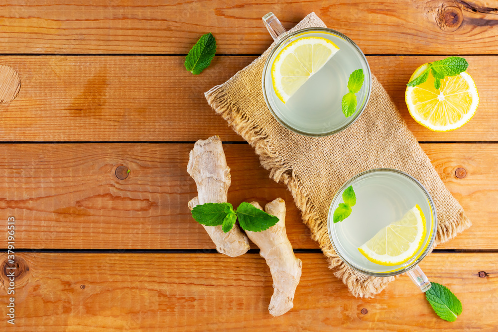 Ginger tea with lemon on a burlap napkin. Two cups of ginger tea with mint on wooden background. Top view Ginger tea with lemon on a burlap napkin. Two cups of ginger tea with mint on wooden background. Top view