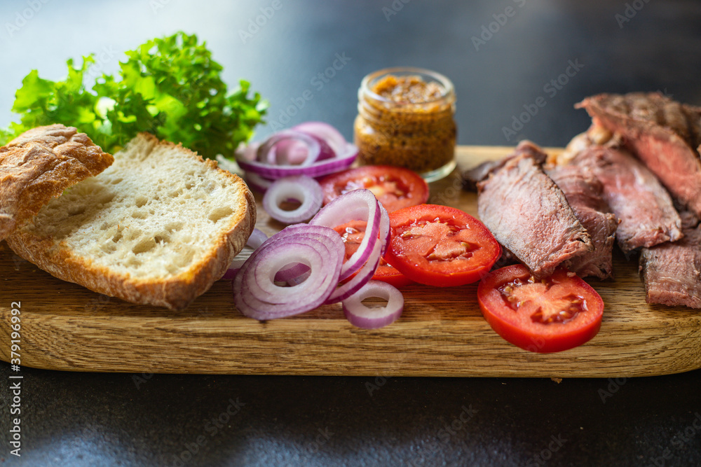 sandwich meat and vegetables loaf of bread, tomato, lettuce, medium or rare steak on the table serving size top view copy space for text food background rustic sandwich meat and vegetables loaf of bread, tomato, lettuce, medium or rare steak on the table serving size top view copy space for text food background rustic