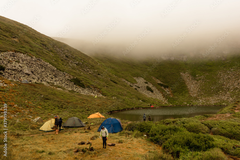 Morning rain and fog near a mountain lake, Carpathian lake Brebeneskul, a tent camp in the fog.