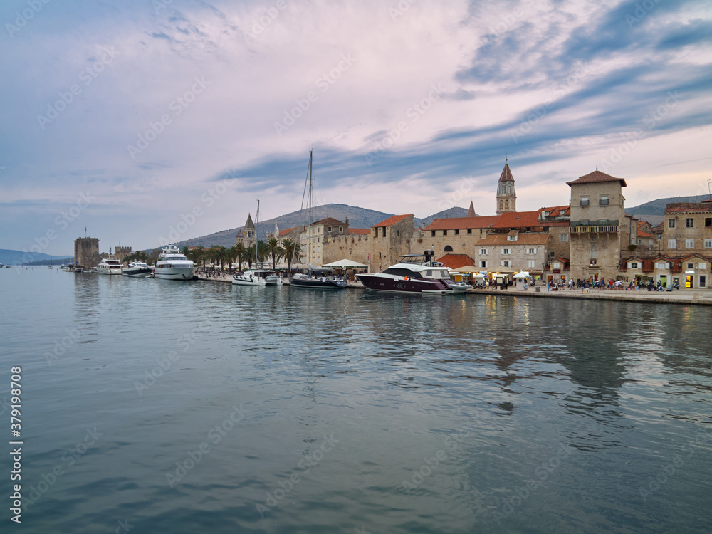 Trogir / Dalmatia / Croatia 24 August 2020 A marina with luxury yachts, a promenade with palm trees and the historic old town of Trogir. City view after sunset during the blue hour.