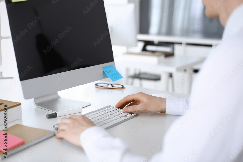 Businessman and woman are discussing questions while using computer and blocknote in modern office, close-up. Teamwork in business Businessman and woman are discussing questions while using computer and blocknote in modern office, close-up. Teamwork in business