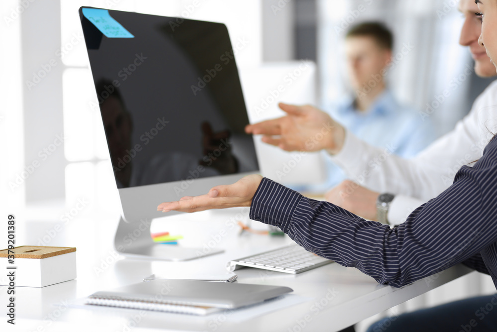 Business woman and man are discussing questions while using computer and blocknote in modern office, close-up. Teamwork in business Business woman and man are discussing questions while using computer and blocknote in modern office, close-up. Teamwork in business