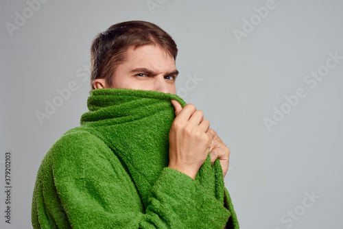 Bearded man in green robe cropped view gray background close-up