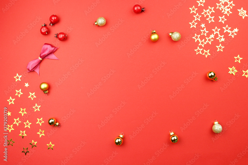 Fototapeta premium christmas decoration on red background with golden confetti stars, balls, berries. Concept holiday atmosphere, new year, celebration, greeting card. Flatlay, top view, frame, copyspace