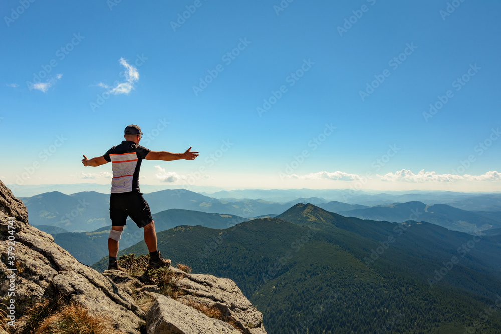 A tourist on top of a large stone block, the top of Smotrych mountain, one of the rocky peaks of the Ukrainian Carpathians.
