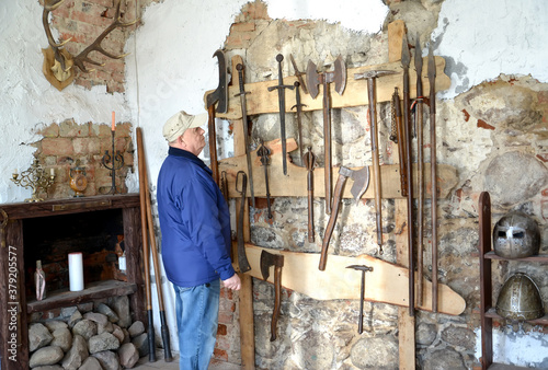 An elderly tourist considers old knives in the museum. Shaaken Castle, XIII century. Kaliningrad region photo