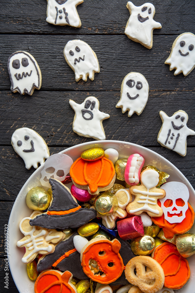 Halloween Jack o Lantern candy bowl with candy and halloween cookies Trick or Treat on black wooden background Halloween Jack o Lantern candy bowl with candy and halloween cookies Trick or Treat on black wooden background