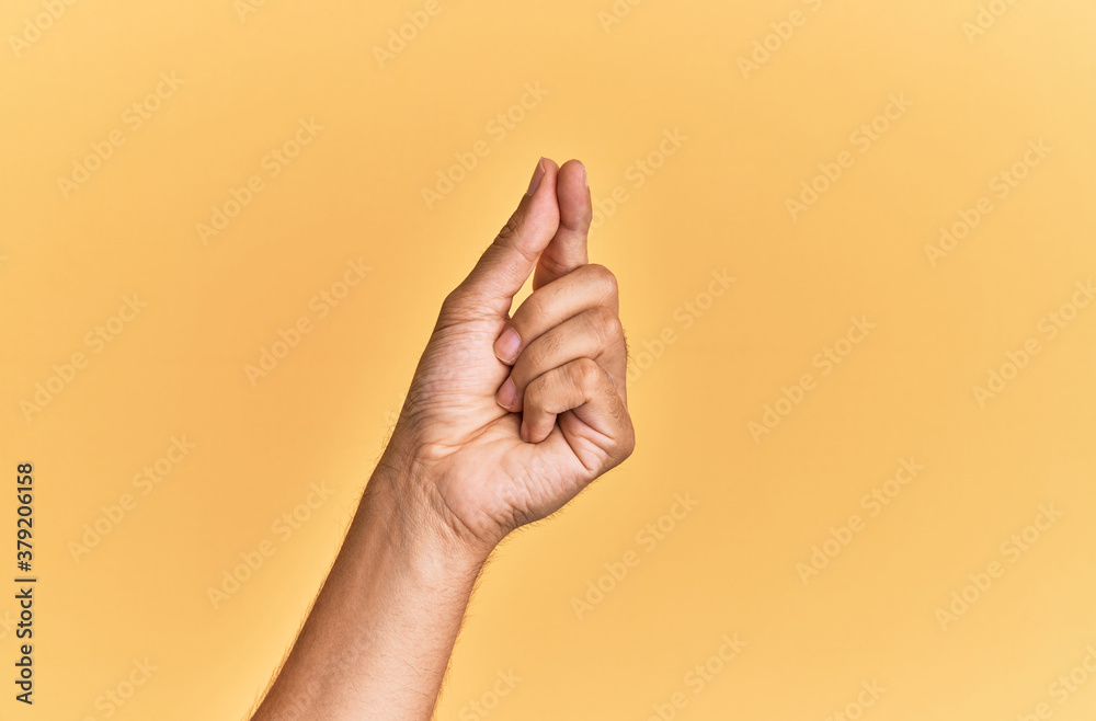 Arm and hand of caucasian man over yellow isolated background holding blank space with thumb finger, business and advertising