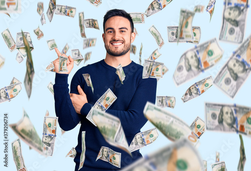 Young handsome man wearing casual clothes with a big smile on face, pointing with hand and finger to the side looking at the camera. photo