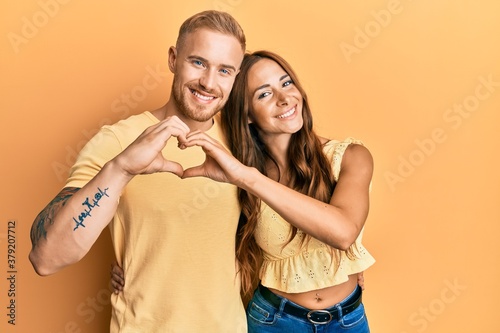 Young couple of girlfriend and boyfriend hugging and standing together smiling in love doing heart symbol shape with hands. romantic concept. © Krakenimages.com