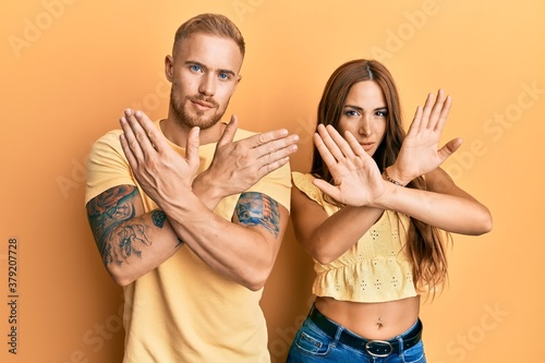 Young couple of girlfriend and boyfriend hugging and standing together rejection expression crossing arms doing negative sign, angry face