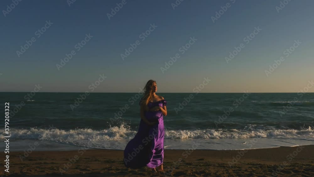 Young woman in dress walking alone by the sea