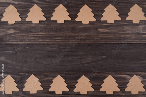 Top above overhead view flat lay photo of rows of christmas tree shaped paper decorations isolated on wooden background with copyspace
