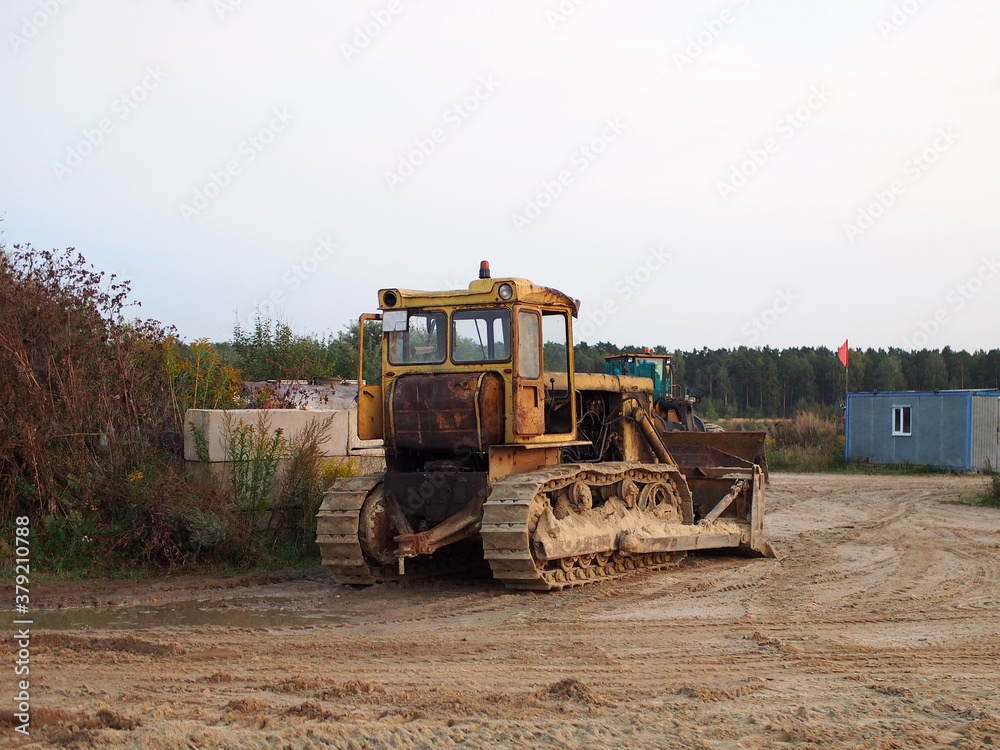 Tractor stands on the background of a construction site. Construction equipment, road construction industry. Tractor stands on the background of a construction site. Construction equipment, road construction industry.