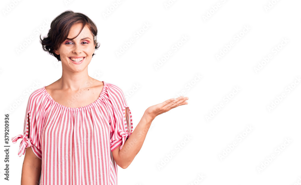 Beautiful young woman with short hair wearing casual summer clothes smiling cheerful presenting and pointing with palm of hand looking at the camera. Beautiful young woman with short hair wearing casual summer clothes smiling cheerful presenting and pointing with palm of hand looking at the camera.