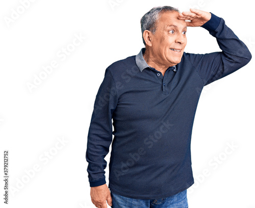 Senior handsome man wearing casual polo very happy and smiling looking far away with hand over head. searching concept.