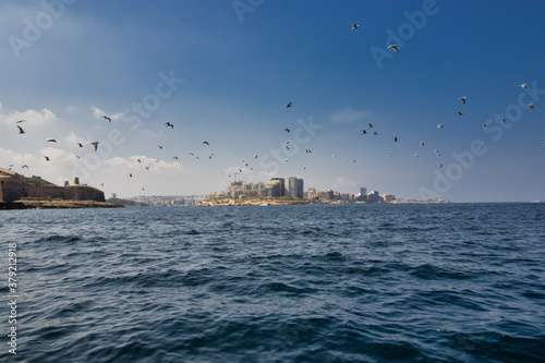 Aerial view of Sliema city. view from sea with birds flying Buildings, apartments, blue sky, Mediterranean sea. Malta island