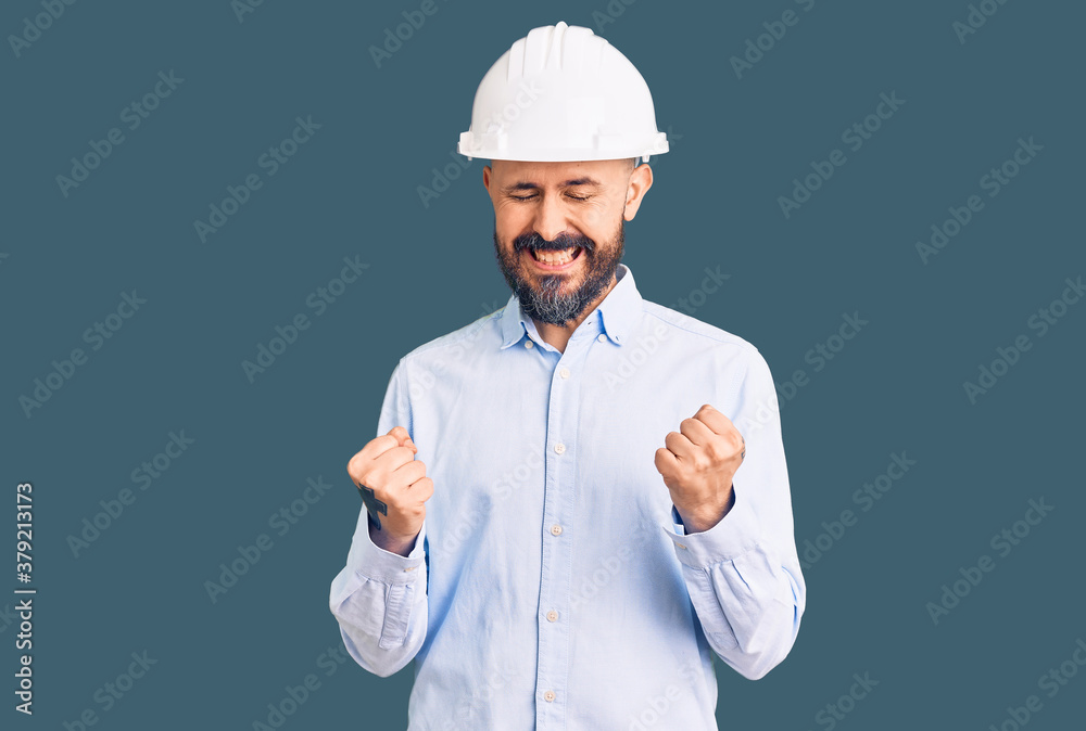 Young handsome man wearing architect hardhat excited for success with arms raised and eyes closed celebrating victory smiling. winner concept.