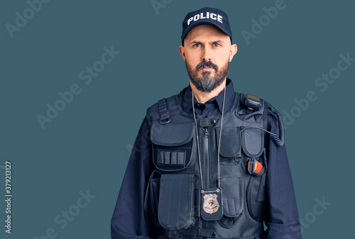 Young handsome man wearing police uniform relaxed with serious expression on face. simple and natural looking at the camera.